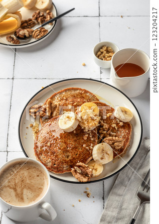 Healthy oatmeal pancakes with banana, nuts and honey on white tile background. Morning food breakfast concept. Pancake day or Maslenitsa recipe 123204217