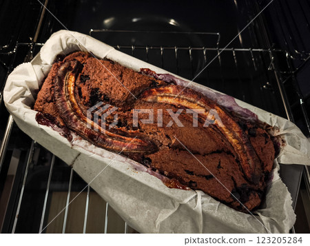 Warm blueberry banana bread cooling in rustic baking pan, golden surface glistening with homemade goodness inside sunlit kitchen for Mother's Day Valentines 123205284