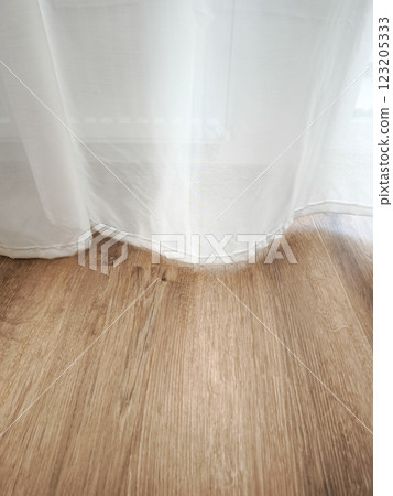 Soft sunlight streaming through white curtain, casting gentle shadows on warm wooden flooring inside minimalist prague apartment interior copy space 123205333