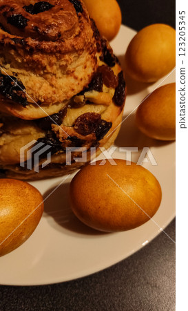 Golden brown easter bread with raisins and dyed eggs creating a festive centerpiece on a white plate 123205345