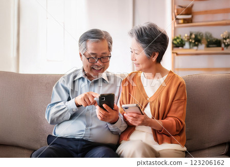 一對老夫婦坐在沙發上，看著智慧型手機螢幕 123206162