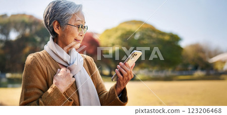 Elderly woman using smartphone while walking in the park 123206468