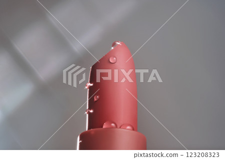 Classic lipstick with drops of water on a neutral background. Classic lipstick with drops of water on a neutral background. 123208323