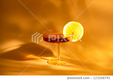 glass of champagne with a slice of orange on an orange background, with hard light 123208741