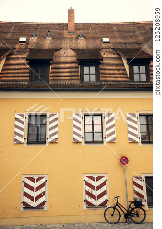 A beautiful European house with classic wooden shutters and a bicycle leaning against its yellow 123208959