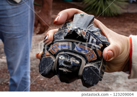 Tourist guide showing an obsidian handcraft to a group of visitors at the Teotihuacan archeological site. 123209004