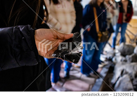 Tourist guide showing an obsidian piece to a group of visitors at the Teotihuacan archeological site. 123209012