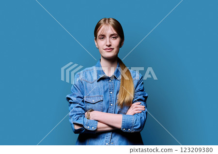 Beautiful young girl with crossed arms looking at camera on blue background Beautiful young girl with crossed arms looking at camera on blue background 123209380
