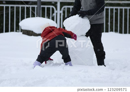 Parents and children making a snowman Parents and children making a snowman 123209571