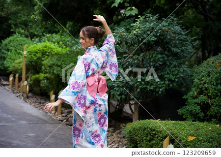 Graceful Woman in Floral Kimono Dancing in Japanese Garden  123209659
