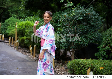 Woman in Floral Kimono Walking Through Serene Japanese Garden  123209660