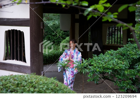 Smiling Woman in Kimono Practicing Mindfulness at Japanese Gate  123209694