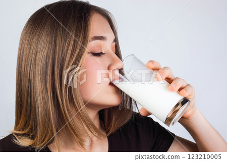 Portrait of a satisfied young woman drinking milk from the glass isolated over light background Portrait of a satisfied young woman drinking milk from the glass isolated over light background 123210005
