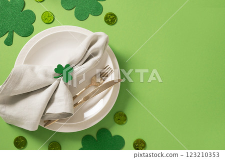 St Patrick's Day table setting with white plate, traditional decoration, shamrock, clover leaves on green background. View from above. Copy space. St Patrick's Day table setting with white plate, traditional decoration, shamrock, clover leaves on green background. View from above. Copy space. 123210353