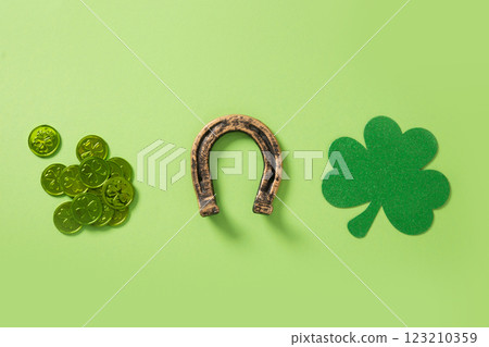 St. Patrick's day composition with clover leaf, green coins and horseshoe on light green background. View from above. Copy space. St. Patrick's day composition with clover leaf, green coins and horseshoe on light green background. View from above. Copy space. 123210359