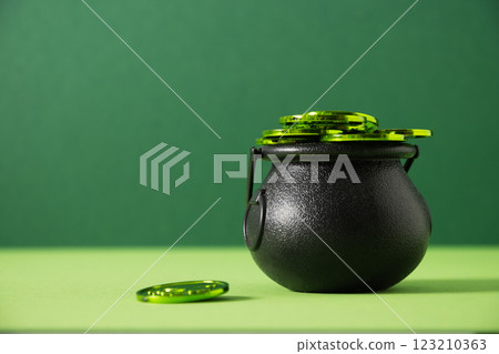 St. Patrick's day black pot, treasure of leprechaun, pot full of green coins on festive green background. Close up. Greeting card. 123210363