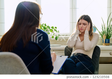 Sad unhappy young woman at therapy with female professional psychologist 123210508