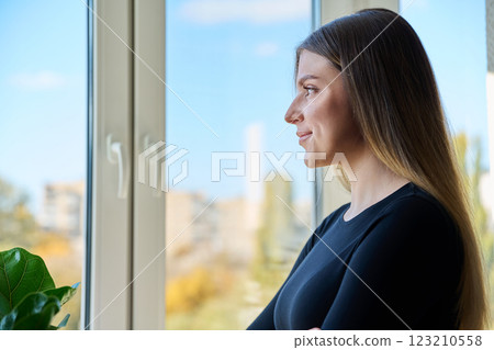 Relaxed happy young woman looking out the window at home 123210558