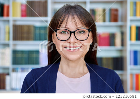 Headshot portrait of friendly mature woman in glasses inside library office 123210581