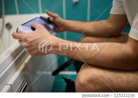 A Man Engaged in a Leisurely Activity While Relaxing in a Comfortable Bathroom Setting A Man Engaged in a Leisurely Activity While Relaxing in a Comfortable Bathroom Setting 123211150
