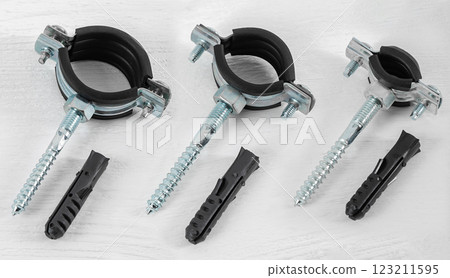 Clamp with fasteners on a white wooden background. Pipe holder. 123211595