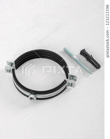 Clamp with fasteners on a white wooden background. Pipe holder. Clamp with fasteners on a white wooden background. Pipe holder. 123211596