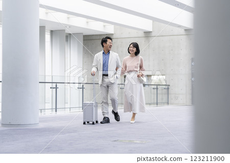 一對 50 多歲的夫婦面帶微笑，拎著包包散步 123211900