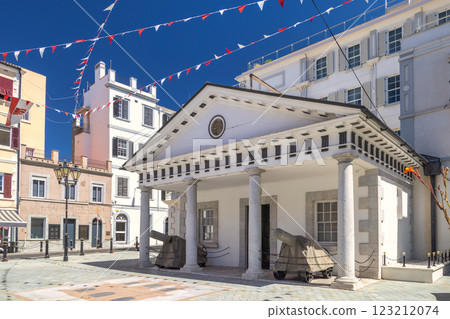 Gibraltar, British Overseas Territory and city on the Iberian Peninsula. Historic building with cannons in a sunny European city square. Festive flags add a celebratory touch. 123212074