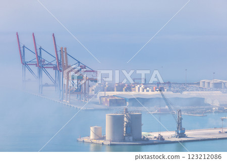 Malaga, seaside city in Andalusia, Spain, Europe. Cargo port in hazy conditions, cranes and containers visible. 123212086