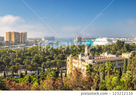 Malaga, seaside city in Andalusia, Spain, Europe. Coastal city harbor view with buildings and cruise ships. Lush greenery surrounds a grand building overlooking the water. 123212110