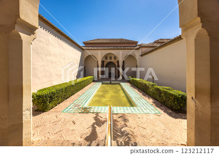 Alcazaba, palace and fortification in Malaga city at Andalusia, Spain, Europe. Serene courtyard with a reflecting pool and lush greenery, framed by elegant arches and aged walls. Alcazaba, palace and fortification in Malaga city at Andalusia, Spain, Europe. Serene courtyard with a reflecting pool and lush greenery, framed by elegant arches and aged walls. 123212117