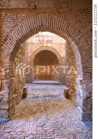 Castle of Gibralfaro in Malaga city at Andalusia, Spain, Europe. Ancient brick archways and intricate brickwork flooring lead into a dimly lit passageway. Castle of Gibralfaro in Malaga city at Andalusia, Spain, Europe. Ancient brick archways and intricate brickwork flooring lead into a dimly lit passageway. 123212159