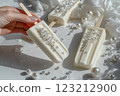 The hand holds an ice cream on a stick, decorated with edible pearls,popsicle, rhinestones. 123212900