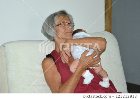 A gray-haired grandmother holding a newborn baby 123212918