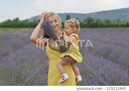Mother and daughter in yellow dresses with basket and bouquet of lavender in lavender field in Provence 123212943