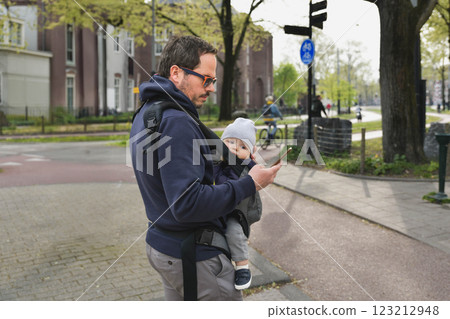 A father carrying his child in a baby sling 123212948