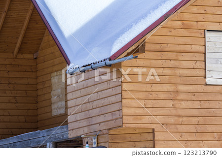 Detail of new wooden ecological traditional cottage of natural lumber materials with steep roof covered with snow on sunny winter day. Old traditions and modern professional construction concept. 123213790