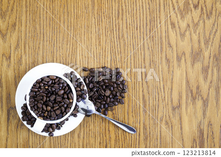 Cup of coffee in a white cup and coffee beans on wooden table background, top view. Cup of coffee in a white cup and coffee beans on wooden table background, top view. 123213814