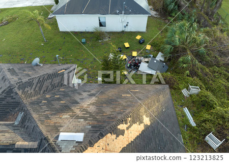 Consequences of natural disaster. Damaged house roof with missing shingles after hurricane Ian in Florida Consequences of natural disaster. Damaged house roof with missing shingles after hurricane Ian in Florida 123213825