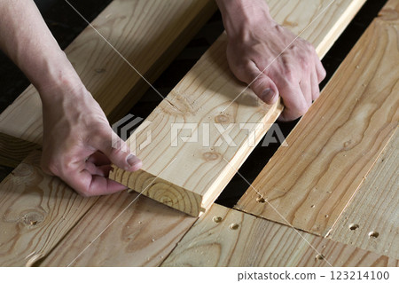 Close up of strong muscular hands of professional carpenter installing natural wooden new planks on wooden frame floor Reconstruction, improvement, renovation and carpentry concept. Close up of strong muscular hands of professional carpenter installing natural wooden new planks on wooden frame floor Reconstruction, improvement, renovation and carpentry concept. 123214100
