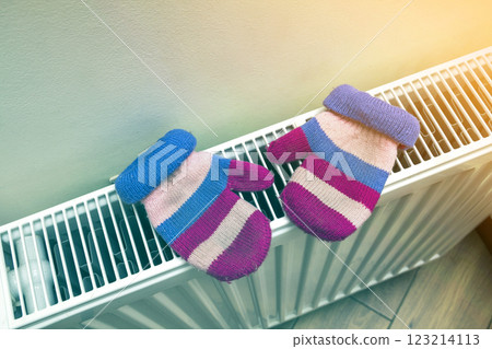 Children's warm hand knitted striped woolen gloves drying on heating radiator after winter day outside Children's warm hand knitted striped woolen gloves drying on heating radiator after winter day outside 123214113