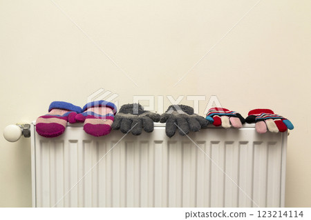 Children's warm hand knitted striped woolen gloves drying on hea Children's warm hand knitted striped woolen gloves drying on hea 123214114