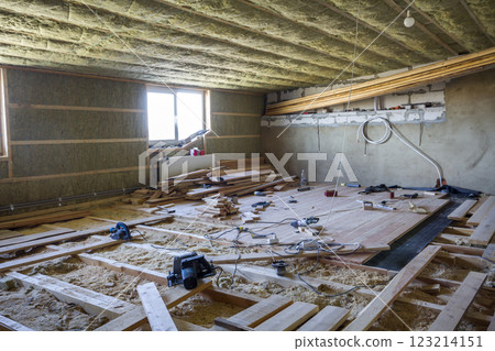 Big spacious light empty attic room under construction and renovation. Mansard floor and ceiling insulation with rock wool. Fiberglass insulation staff in wooden frame for cold barrier. 123214151