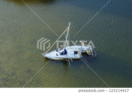 Aerial view of sunken sailboat on shallow bay waters after hurricane in Manasota, Florida Aerial view of sunken sailboat on shallow bay waters after hurricane in Manasota, Florida 123214427