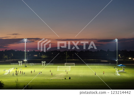 Aerial view of public sports park with people engaged in football game on grass stadium at sunset. Active way of life concept Aerial view of public sports park with people engaged in football game on grass stadium at sunset. Active way of life concept 123214442