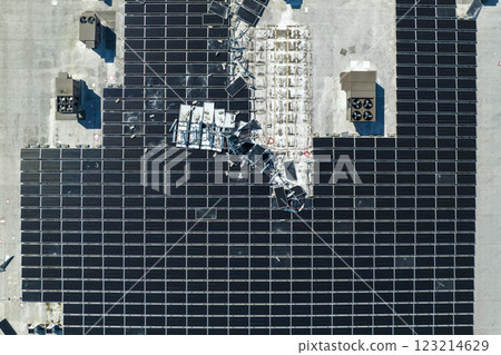 Aerial view of damaged by hurricane wind photovoltaic solar panels mounted on industrial building roof for producing green ecological electricity. Consequences of natural disaster 123214629