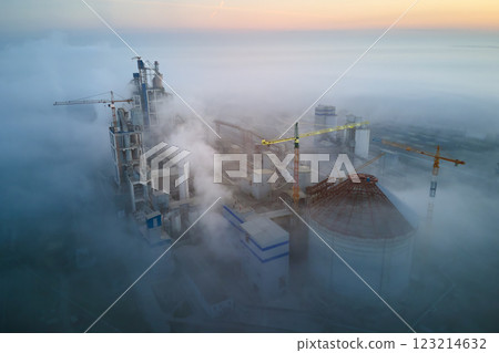 Aerial view of cement factory with high concrete plant structure and tower crane at industrial production site on foggy morning. Manufacture and global industry concept. Aerial view of cement factory with high concrete plant structure and tower crane at industrial production site on foggy morning. Manufacture and global industry concept. 123214632