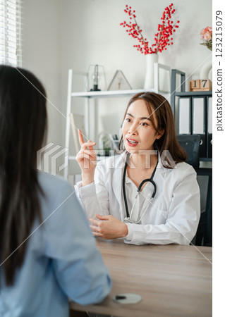 Female doctor in white coat discussing with patient in a bright, modern medical office setting. 123215079