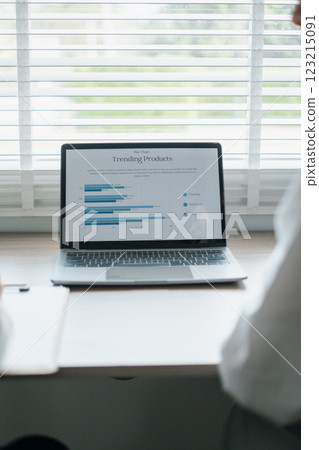 Business professionals reviewing data on a laptop displaying graphs and charts in a bright office environment. 123215091