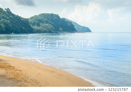 Tranquil beach with calm waters and distant hills Tranquil beach with calm waters and distant hills 123215787